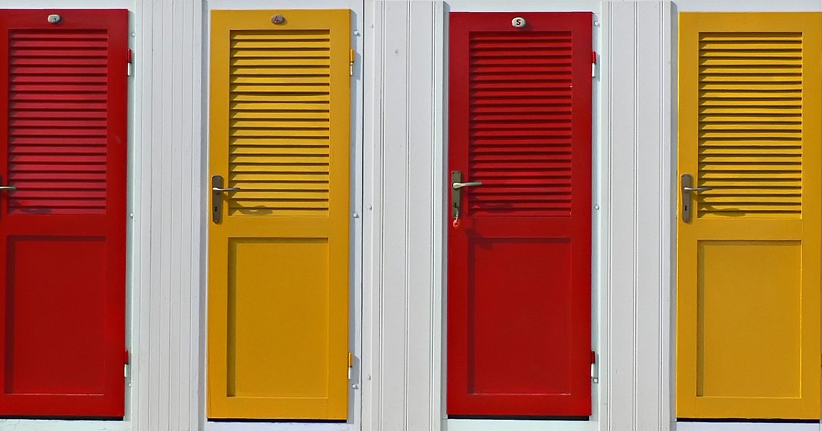 A row of brightly painted doors side by side on a white wall