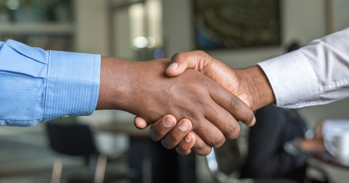 Two people shaking hands across a desk