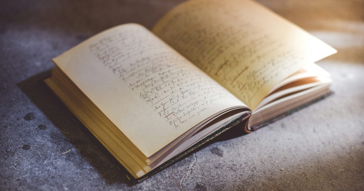 An open book of handwritten pages lit from one side