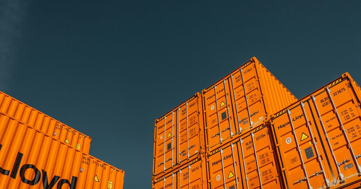 Shipping containers stacked in separate blocks against a blue sky