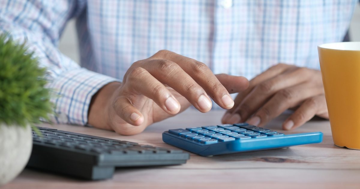 Hands working through figures on a desk calculator