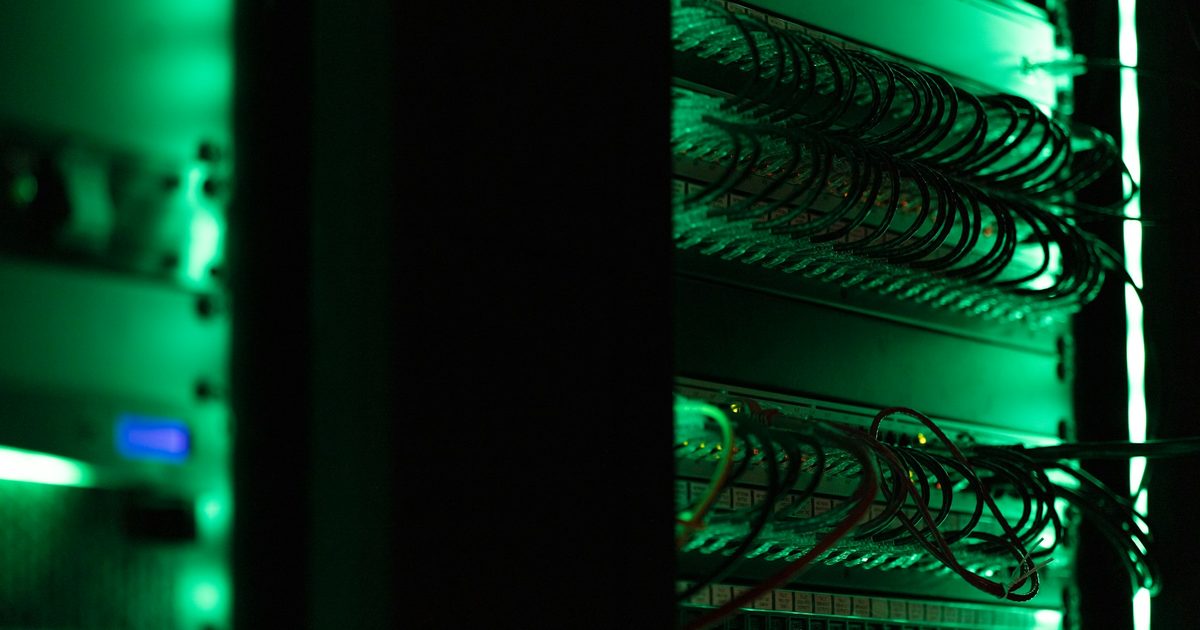 A server rack lit green in a dark room