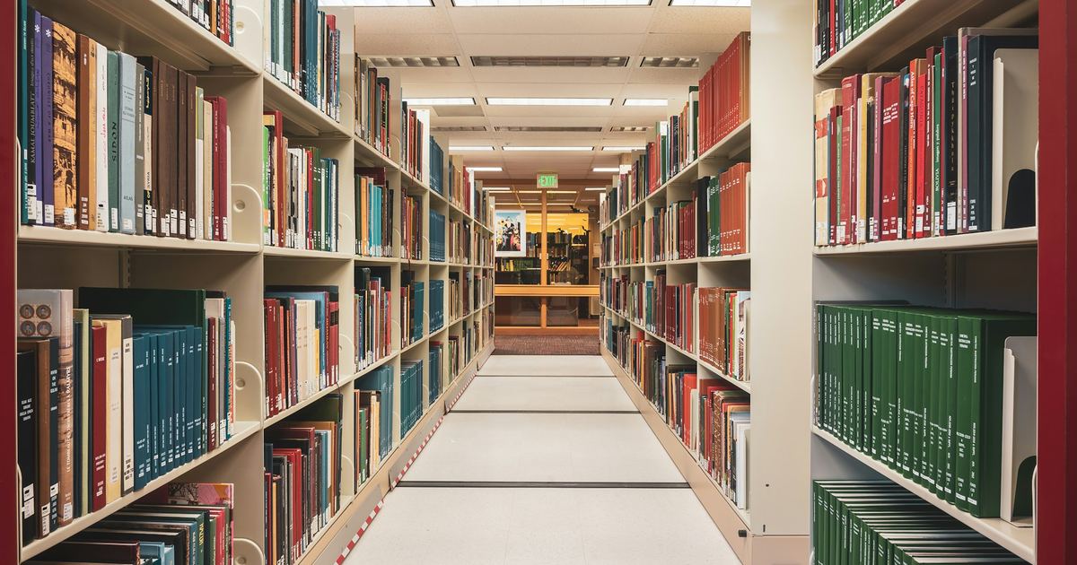A library aisle lined floor to ceiling with shelved books